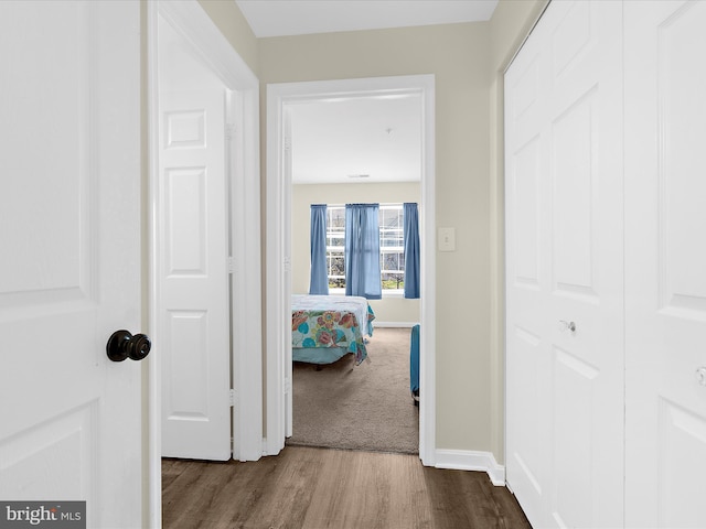 corridor with dark wood finished floors and baseboards