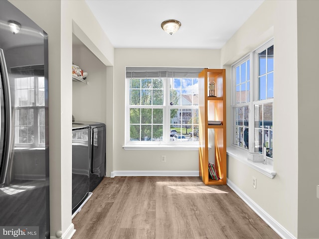 doorway with separate washer and dryer, baseboards, and wood finished floors