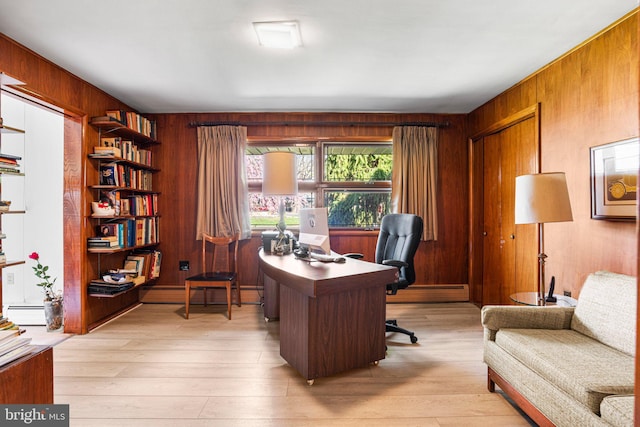 office space with baseboard heating, light wood-type flooring, and wooden walls