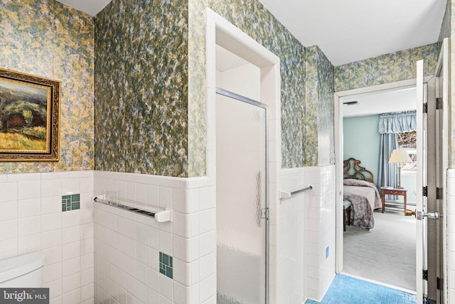 ensuite bathroom featuring ensuite bathroom, wallpapered walls, a stall shower, and wainscoting