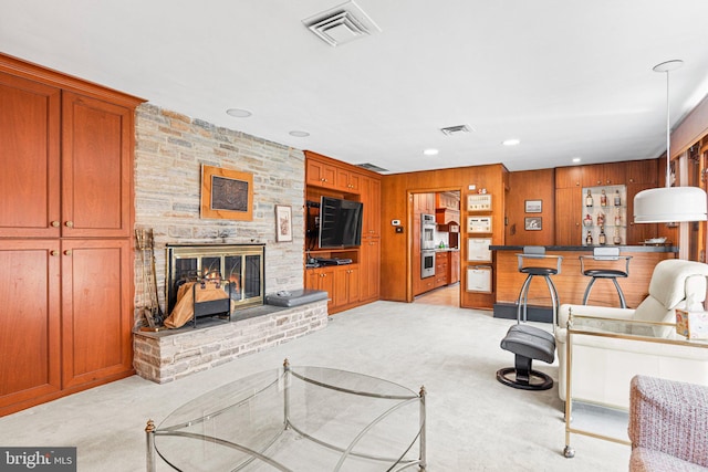 living room with light carpet, visible vents, wood walls, and a fireplace