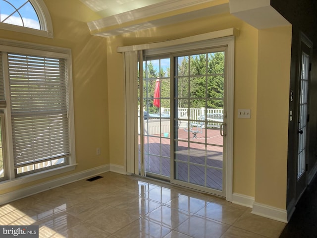 doorway with tile patterned floors, baseboards, and visible vents