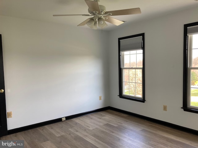 spare room with light wood-style flooring, ceiling fan, and baseboards