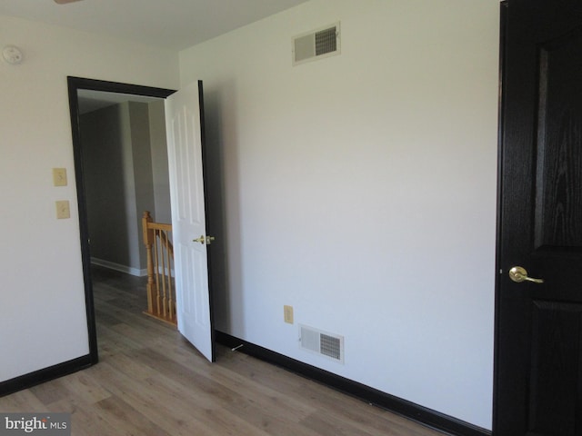 empty room featuring visible vents, baseboards, and light wood-type flooring