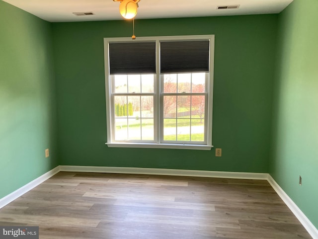 spare room featuring wood finished floors, baseboards, and visible vents