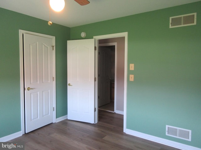 unfurnished bedroom featuring ceiling fan, visible vents, baseboards, and wood finished floors