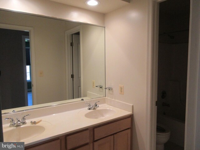 full bathroom with a sink, toilet, and double vanity