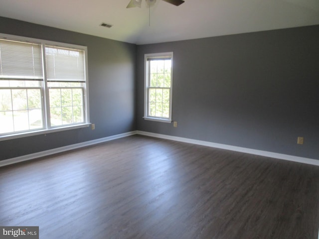 empty room with visible vents, baseboards, a ceiling fan, and dark wood finished floors