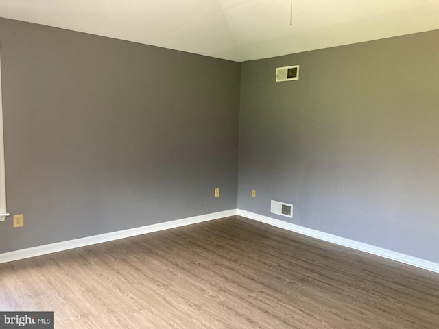 spare room featuring dark wood-type flooring, visible vents, and baseboards