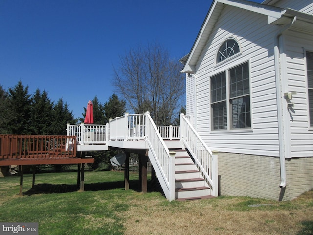 exterior space with stairs, a deck, and a lawn
