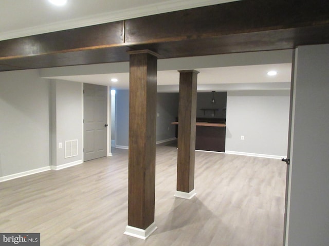 finished below grade area featuring light wood-style floors, baseboards, and visible vents