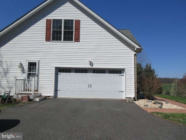 view of side of property featuring an attached garage and aphalt driveway