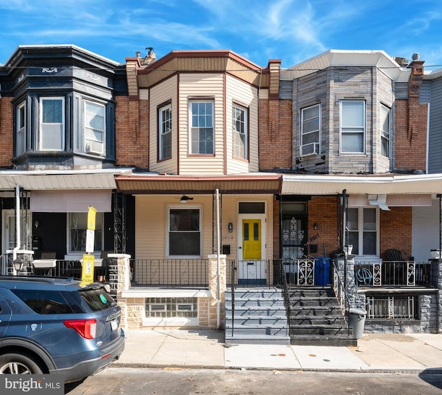 multi unit property featuring brick siding, a porch, and cooling unit