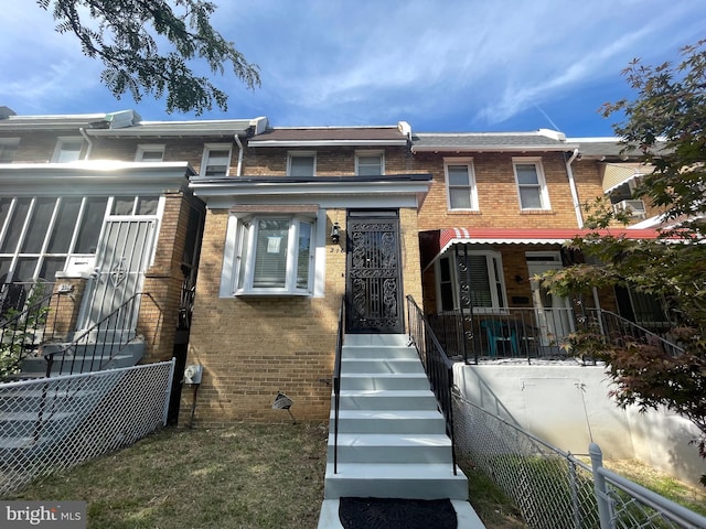 view of property featuring brick siding and fence