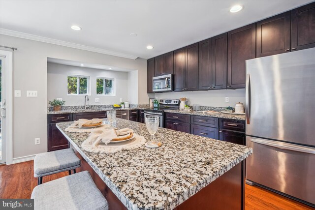 kitchen with light wood-style floors, appliances with stainless steel finishes, a sink, and light stone counters