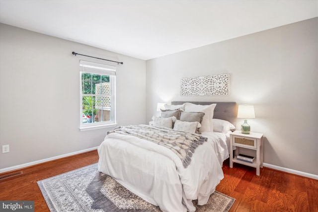 bedroom with visible vents, baseboards, and wood finished floors