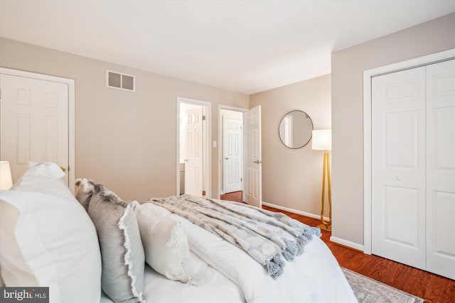 bedroom with a closet, visible vents, baseboards, and wood finished floors