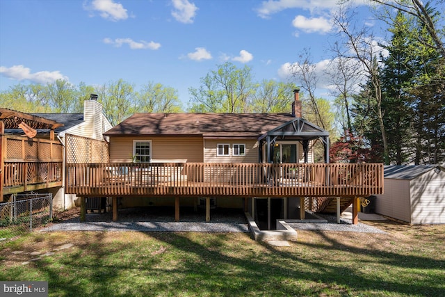 rear view of house featuring a wooden deck, a lawn, and a chimney