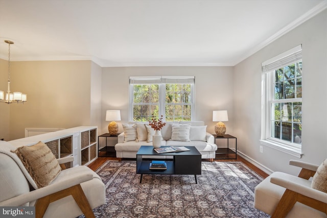 living area with ornamental molding, a chandelier, and wood finished floors