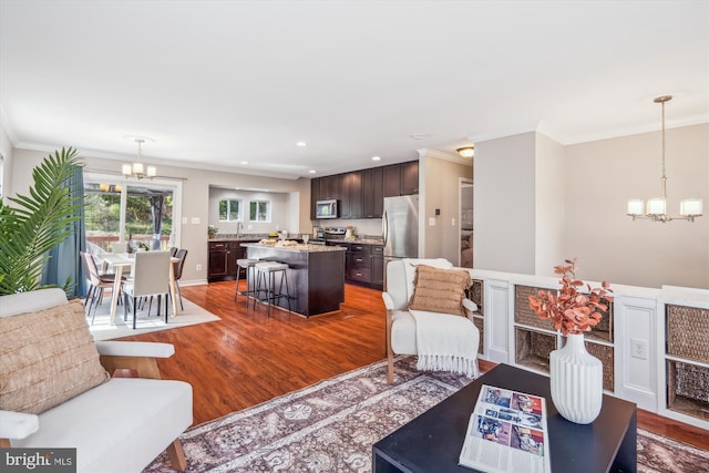living area featuring a chandelier, crown molding, and dark wood-style flooring
