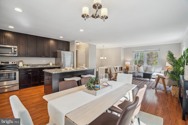 dining room with crown molding, wood finished floors, an inviting chandelier, and recessed lighting