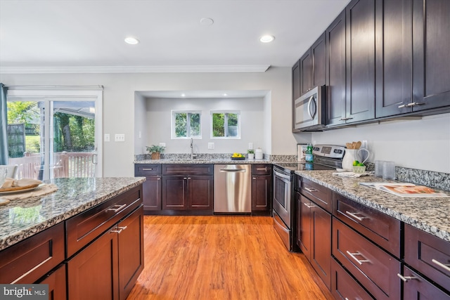 kitchen featuring light stone countertops, plenty of natural light, light wood-type flooring, and appliances with stainless steel finishes