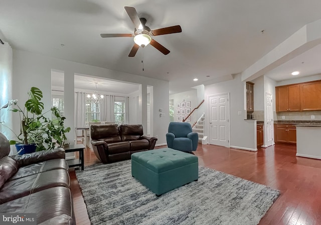 living room featuring baseboards, dark wood-style flooring, stairway, recessed lighting, and ceiling fan with notable chandelier
