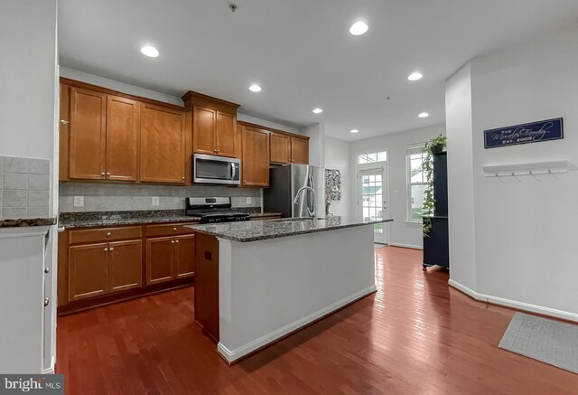 kitchen with dark wood-style flooring, brown cabinets, and stainless steel appliances