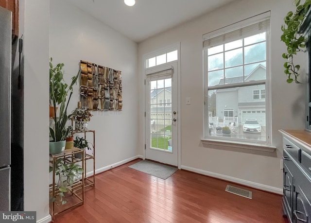 doorway to outside with baseboards, wood-type flooring, and visible vents