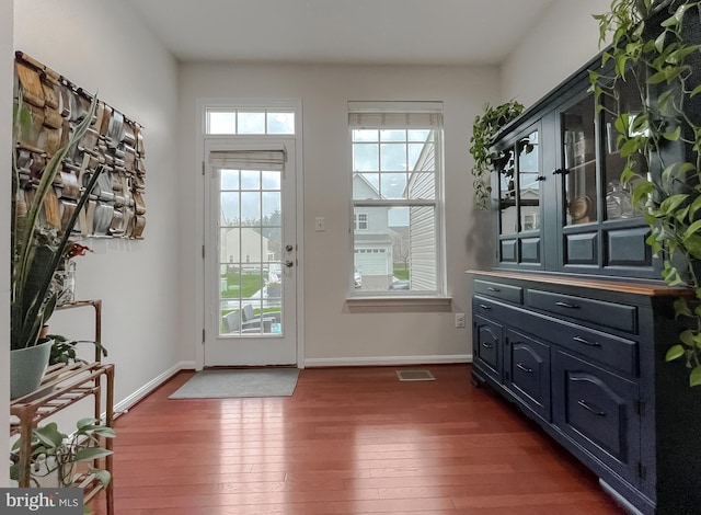 doorway with visible vents, baseboards, and dark wood-style floors