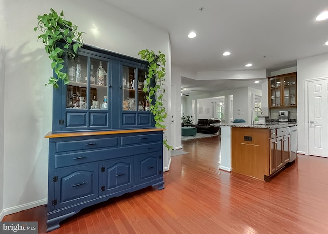 kitchen with glass insert cabinets, baseboards, a sink, open floor plan, and dark wood finished floors