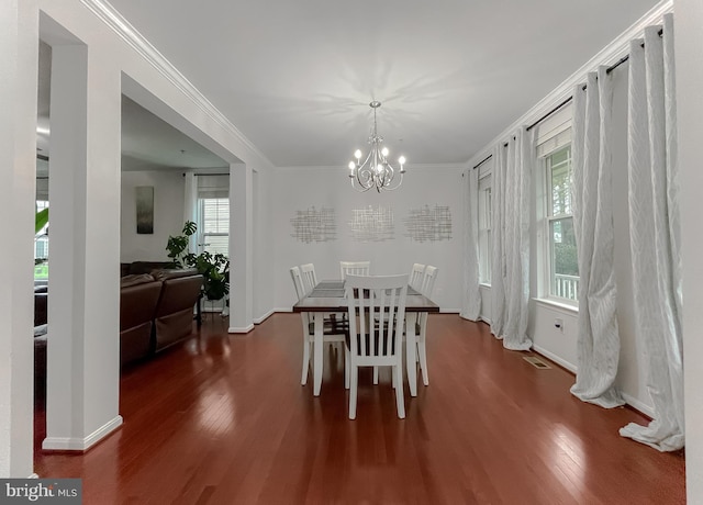 dining space with a chandelier, crown molding, wood finished floors, and baseboards