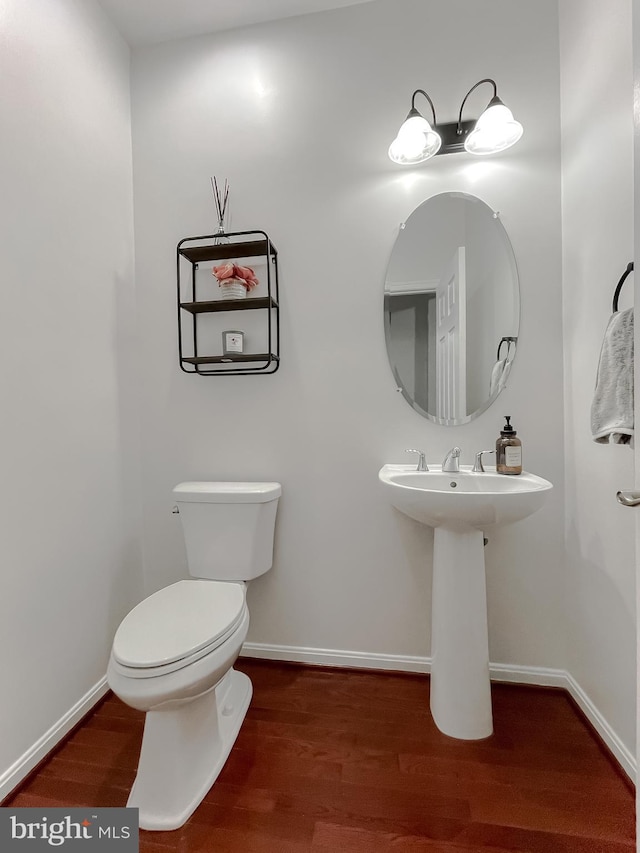 bathroom with toilet, baseboards, and wood finished floors