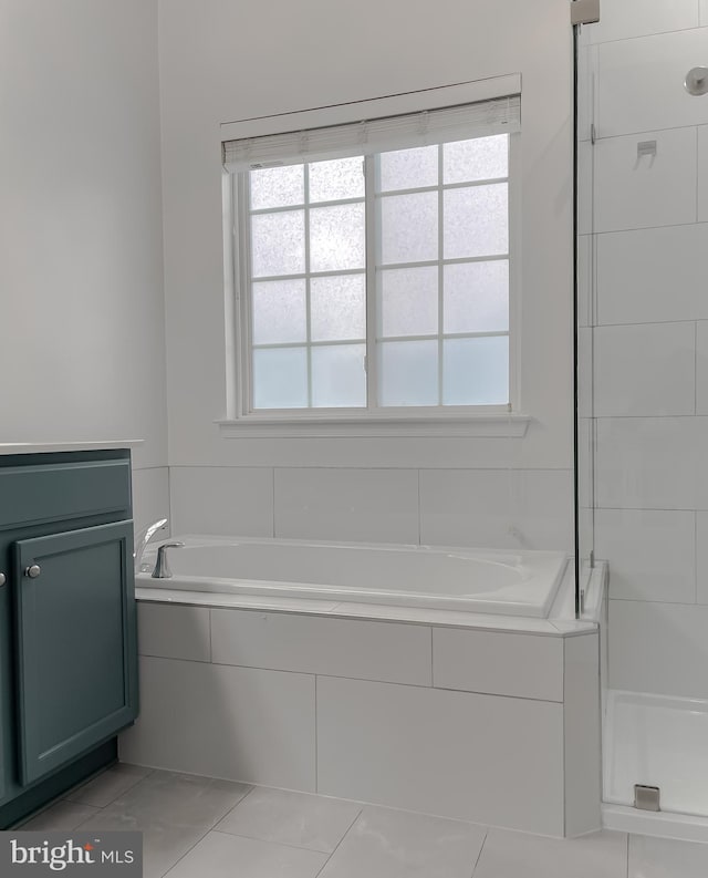 full bath featuring tile patterned floors, plenty of natural light, a stall shower, and a garden tub