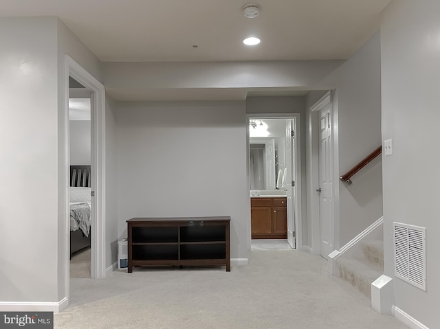 hallway with light carpet, baseboards, and visible vents