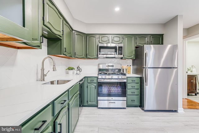 3568 S George Mason Dr Unit 12, Alexandria, VA 22302 - kitchen with a sink, decorative backsplash, light wood-type flooring, appliances with stainless steel finishes, and green cabinetry