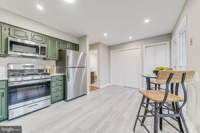 3568 S George Mason Dr Unit 12, Alexandria, VA 22302 - kitchen featuring tasteful backsplash, light wood-type flooring, baseboards, green cabinets, and appliances with stainless steel finishes