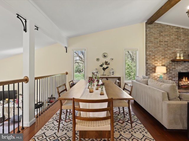 dining area with dark wood-type flooring, a healthy amount of sunlight, a fireplace, and lofted ceiling with beams