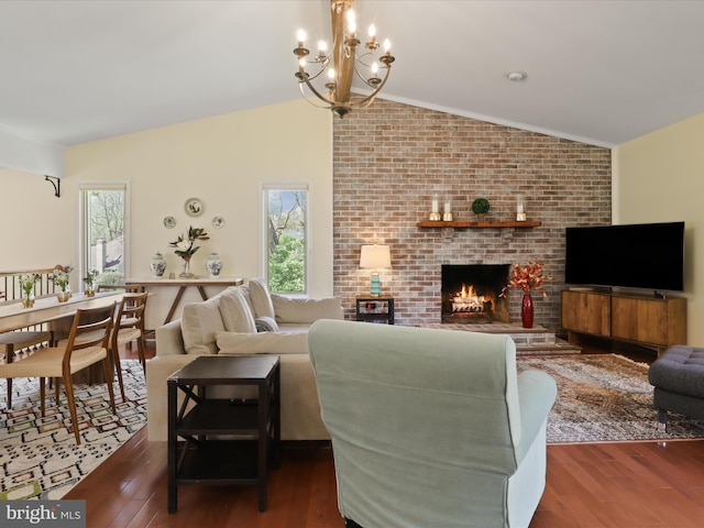 living room with a chandelier, a fireplace, vaulted ceiling, and wood finished floors