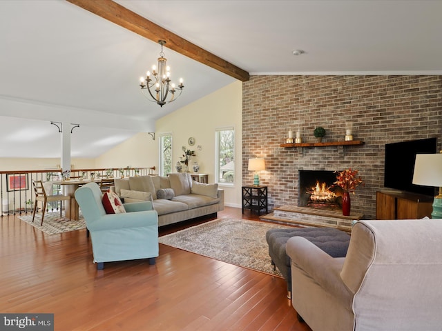 living room with an inviting chandelier, a fireplace, vaulted ceiling with beams, and wood finished floors