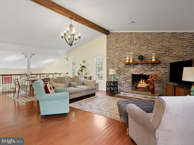 living room with a brick fireplace, an inviting chandelier, wood finished floors, and lofted ceiling with beams