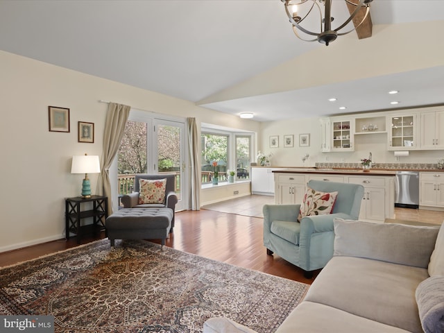 living room with recessed lighting, lofted ceiling, light wood finished floors, baseboards, and a notable chandelier