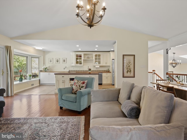 living room with recessed lighting, an inviting chandelier, light wood-style floors, and lofted ceiling
