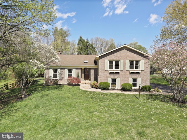 view of front of house with a front yard, fence, brick siding, and a chimney