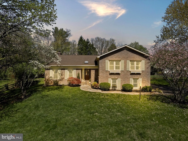 view of front of property featuring brick siding and a lawn