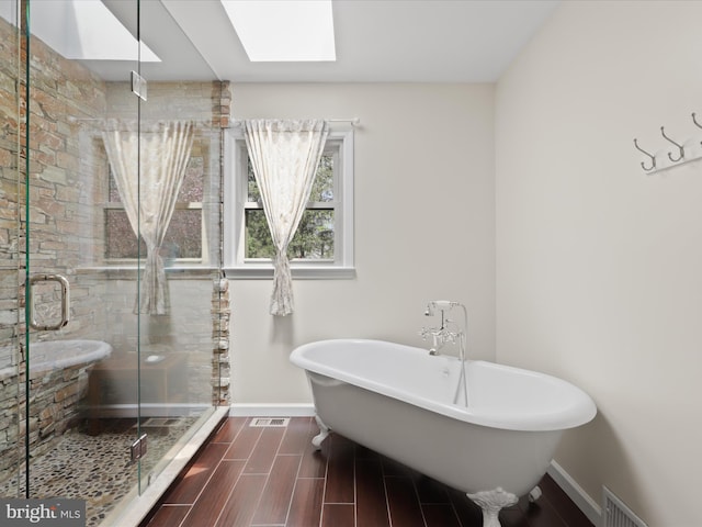 full bathroom with a soaking tub, a shower stall, visible vents, a skylight, and wood tiled floor