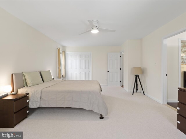 bedroom featuring light carpet, a closet, baseboards, and ceiling fan