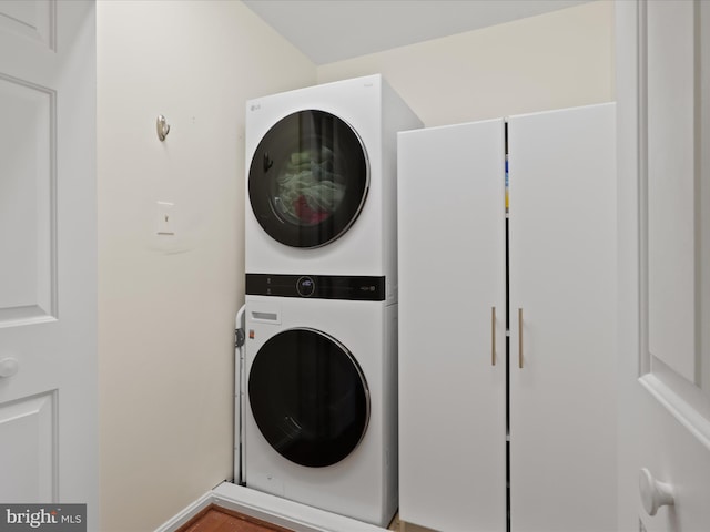 clothes washing area featuring stacked washer and dryer and laundry area