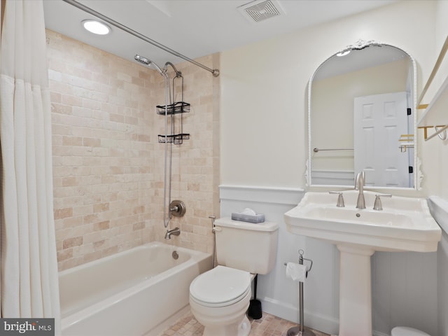 full bath featuring visible vents, toilet, a sink, shower / bath combo with shower curtain, and baseboards