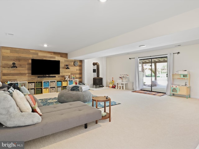 living area featuring wood walls, a wood stove, carpet flooring, and recessed lighting